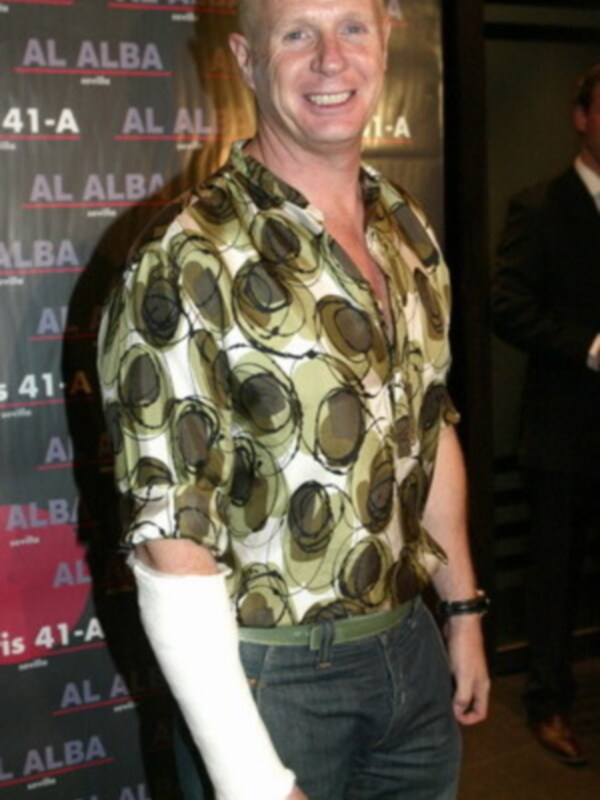 Persona con camisa estampada y brazo vendado, sonriendo en un evento AL ALBA.