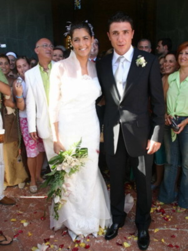 Elegante pareja de novios en un evento formal, rodeados de invitados en un ambiente festivo.