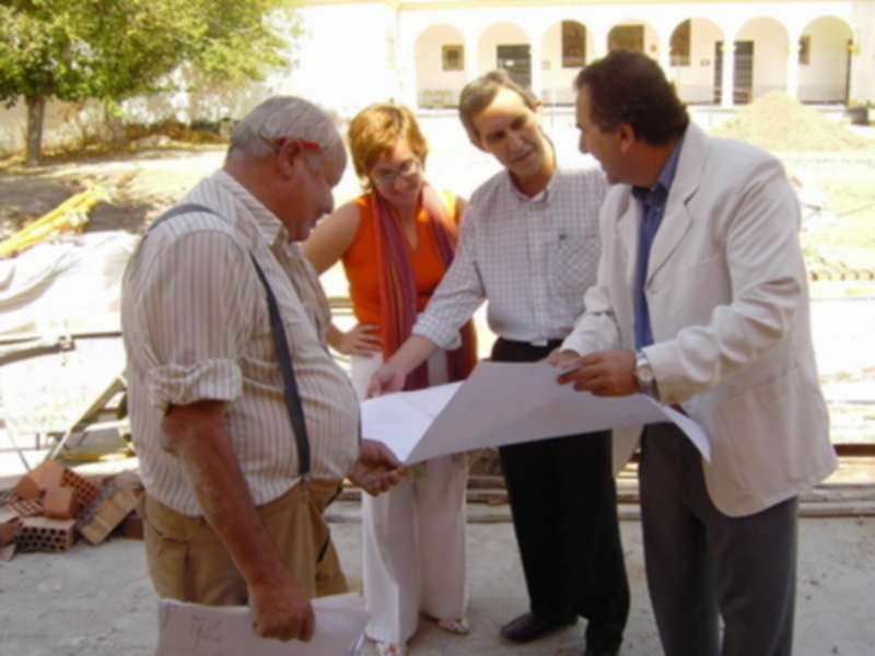 Grupos de personas revisando documentos en un entorno exterior, posiblemente un sitio de construcción o renovación.