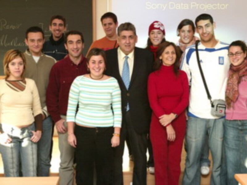 Grupo de estudiantes y profesor posando en una aula con proyector Sony Data Projector en el fondo.