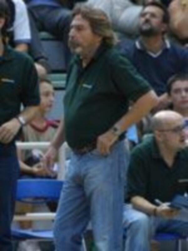 Un entrenador en un partido de baloncesto, gesturando con energía.