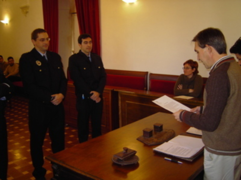 Reunión formal en una sala con mesa de madera, documentos y personas en uniforme.