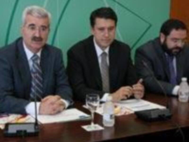 Tres hombres en traje sentados en una mesa durante una reunión o conferencia formal.