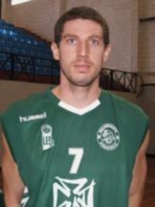 Jugador de baloncesto en uniforme verde con el número 7, posando en una cancha deportiva.