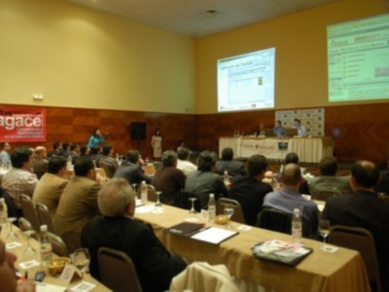 Conferencia en sala con audiencia asistiendo a presentaciones en pantallas de proyección.