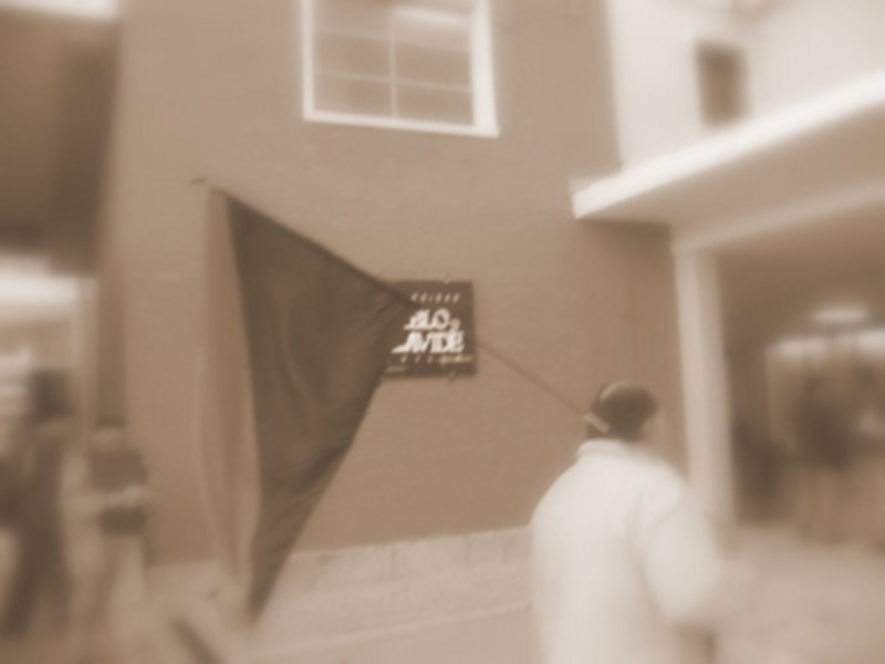Un edificio con una bandera ondeando en el exterior, con una persona caminando en el interior.
