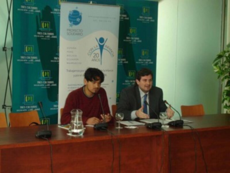 Conferencia de prensa con dos participantes en un escenario formal, con carteles de la Fundación Proyecto Solidario y el logo del evento en el fondo.