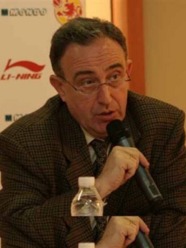 Un hombre con una chaqueta a cuadros hablando en un micrófono durante una conferencia de prensa.