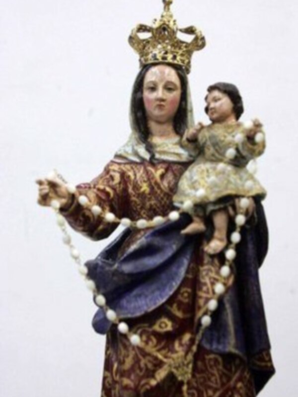 Estatua de la Virgen María con el Niño Jesús, vestida con traje tradicional y corona real, sosteniendo un rosario.