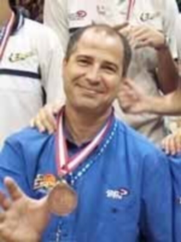 Persona con medalla de oro en el cuello, posando con otros participantes en un evento deportivo.