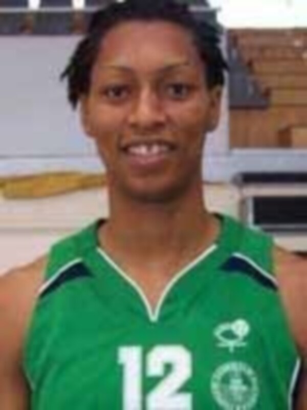 Una jugadora de baloncesto con una camiseta verde y el número 12 en la espalda, posando en una cancha de baloncesto.