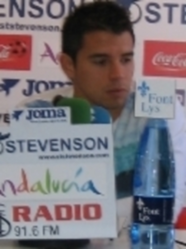 Persona sosteniendo una botella de agua con logotipos de patrocinadores en el fondo.