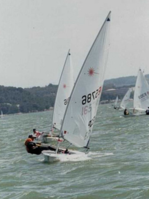 Competición de vela en el mar con barcos navegando en aguas onduladas.
