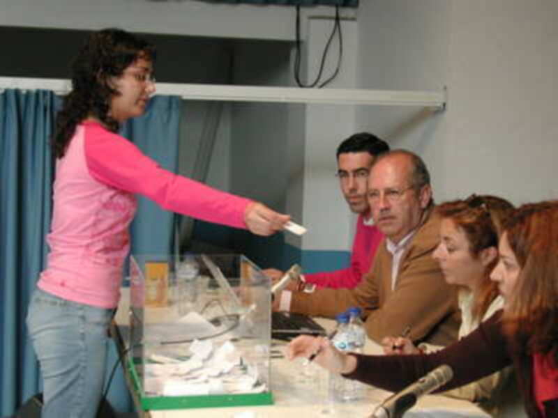 Persona depositando un voto en una urna durante un proceso electoral.