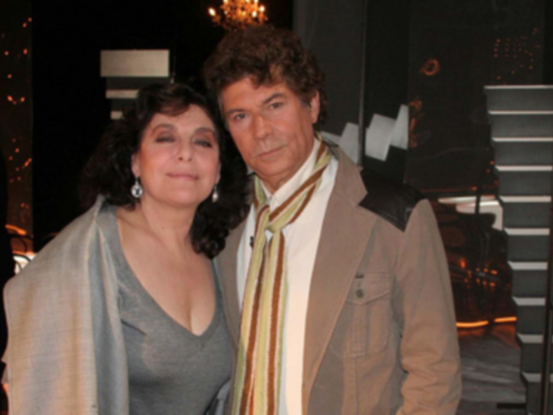 Dos personas posan juntas en un evento nocturno con luces de fondo.