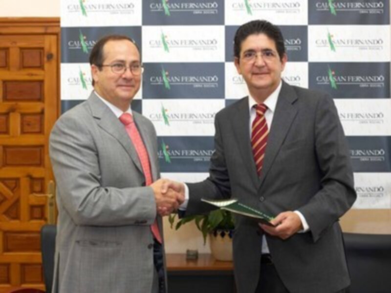 Dos hombres en trajes intercambian un documento en un evento formal.