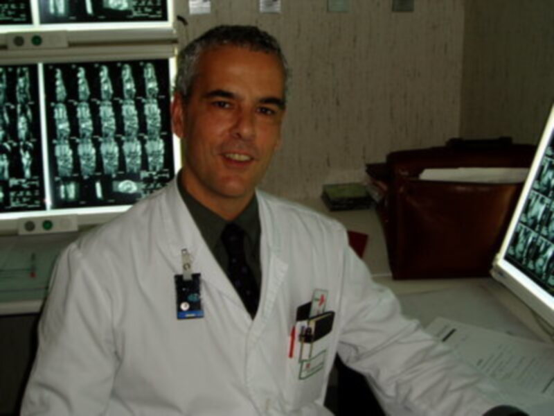 Un médico en una sala de diagnóstico, frente a varios monitores de imágenes médicas.