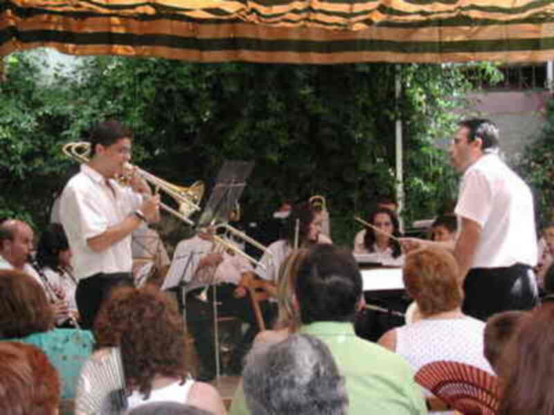 Orquesta de música en un concierto al aire libre bajo un toldo decorativo.