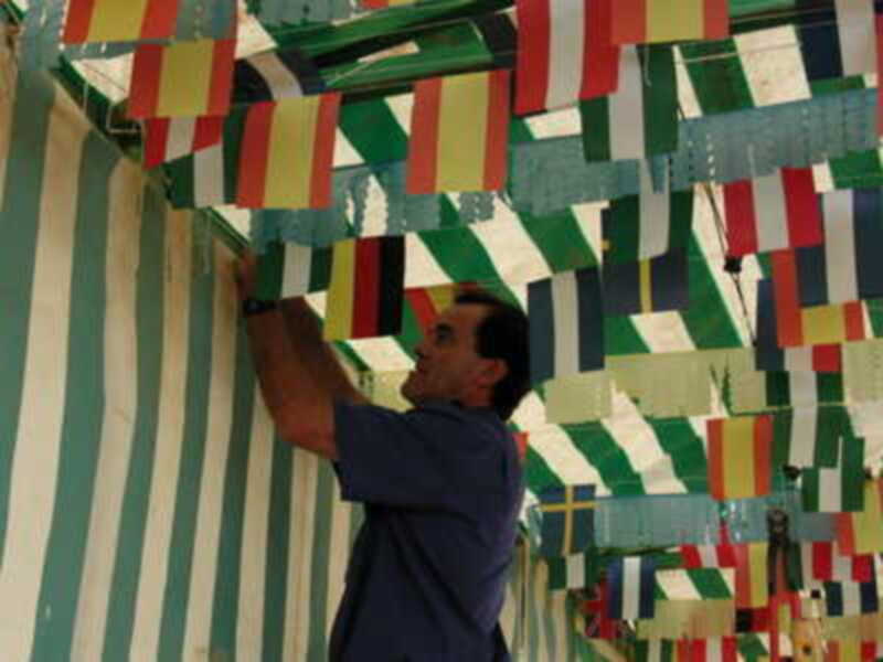 Un hombre coloca banderines de colores en una estructura decorativa.