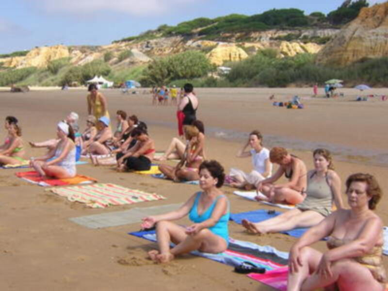 Gente disfrutando de la playa, practicando yoga y relajándose bajo el sol.
