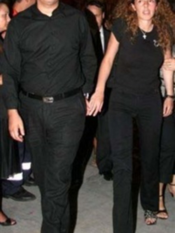 Un hombre y una mujer vestidos de negro caminando juntos en una alfombra roja.