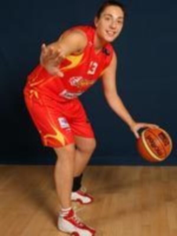 Jugadora de baloncesto en acción, vestida con la camiseta y los pantalones rojos de la selección española, sosteniendo un balón de baloncesto.