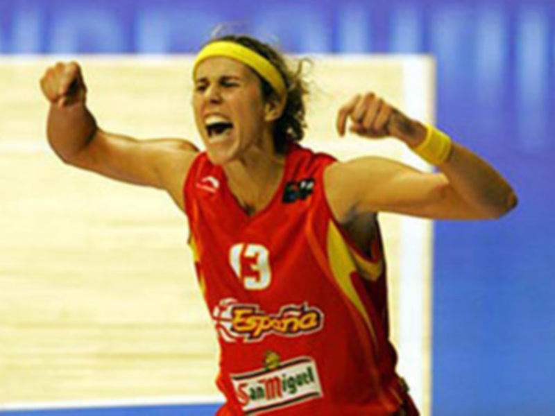 Una jugadora de balonmano celebra su victoria con una sonrisa y una bandera española en su camiseta.