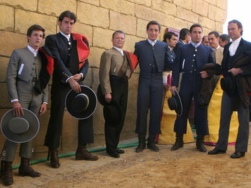 Grupo de hombres en trajes tradicionales posando con sombreros en un entorno rural.