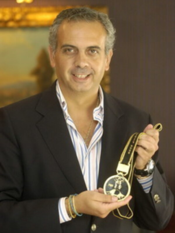Hombre sonriente en traje sosteniendo una medalla de reloj de bolsillo