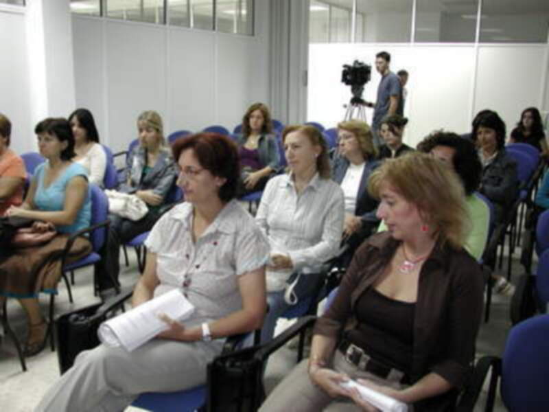 Asistentes participando en una conferencia o seminario en un salón bien iluminado.
