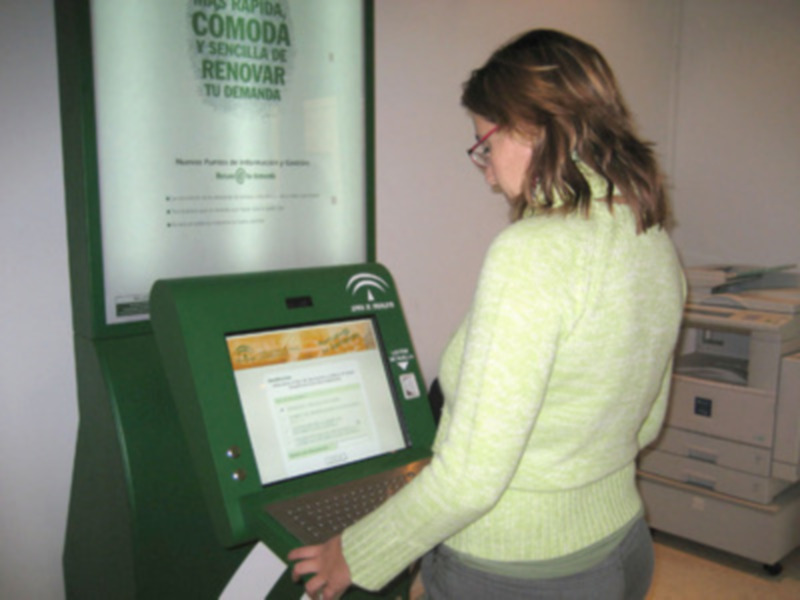 Persona interaccionando con una máquina de renovación de permisos de conducir en un centro de tránsito.