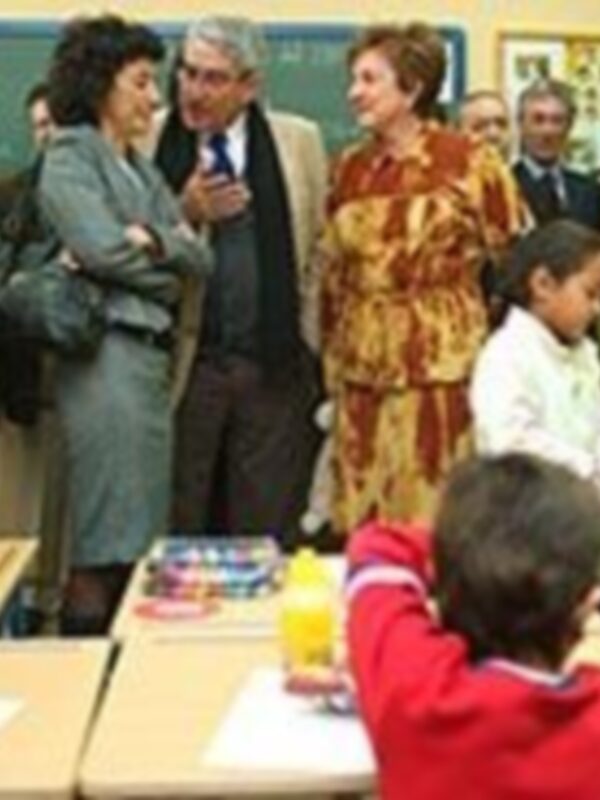 Profesores y estudiantes interaccionan en un aula llena de color y aprendizaje.