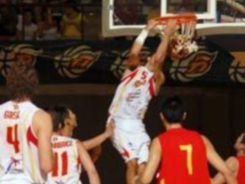 Jugador en acción durante un partido de baloncesto, realizando un mateso en el aro.