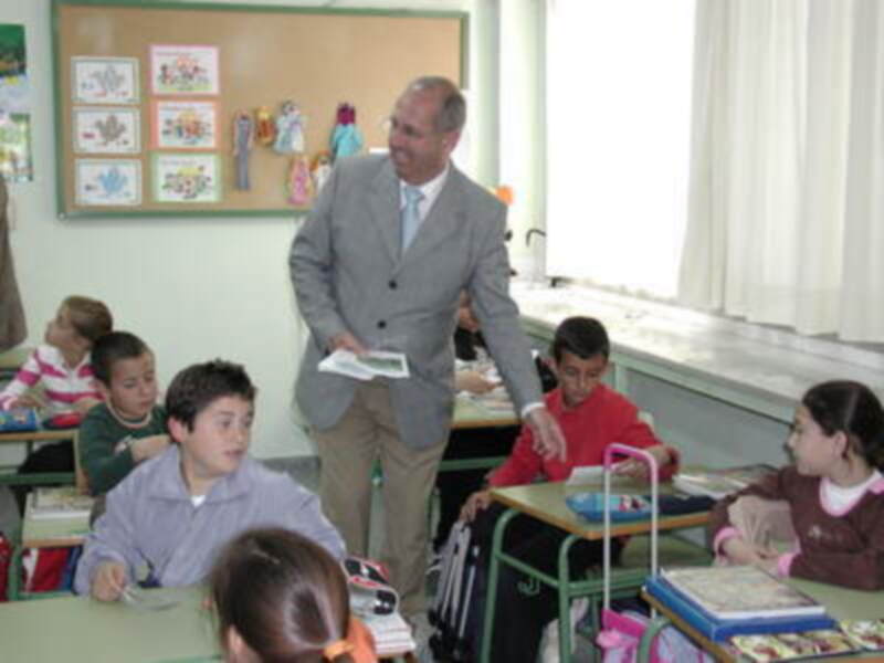 Maestro interactúa con estudiantes en un aula llena de actividad y aprendizaje.