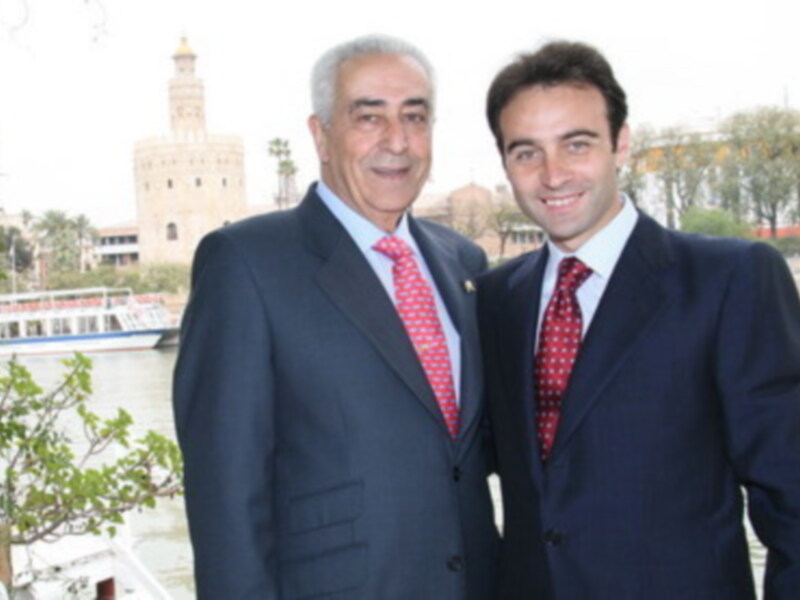 Dos hombres en trajes posan frente a la Torre del Oro en Sevilla, España.