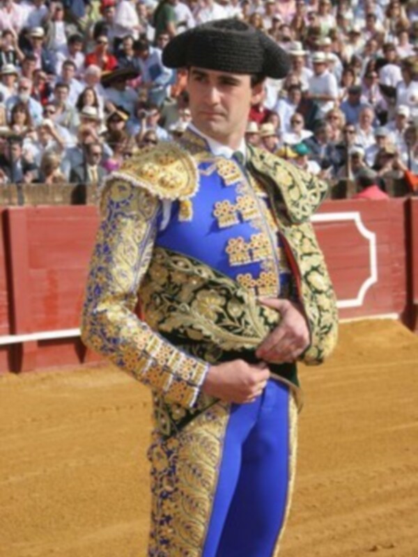 Un torero en traje de luces en una plaza de toros, rodeado por un público atento.