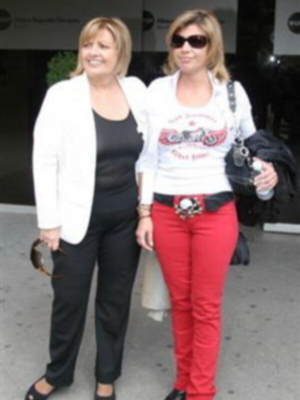 Dos mujeres caminando juntas, una con pantalones rojos y la otra con pantalones negros, en un entorno urbano.