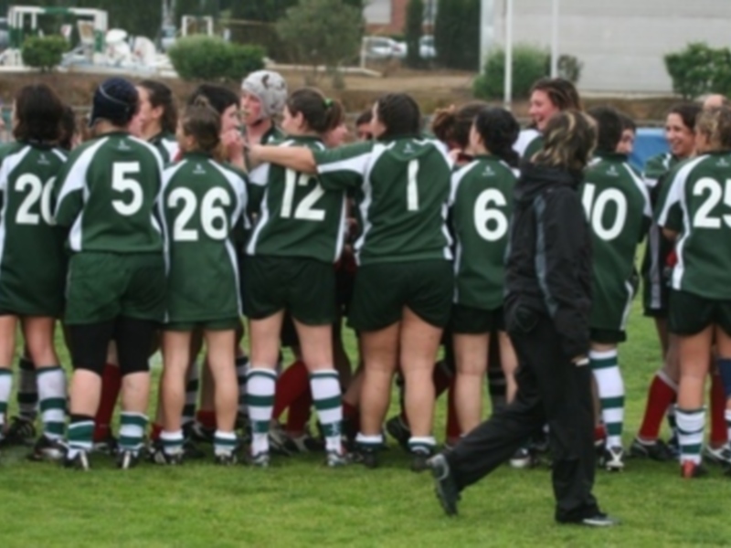 Equipo de fútbol femenino en verde y negro, posando juntos en el campo de juego.