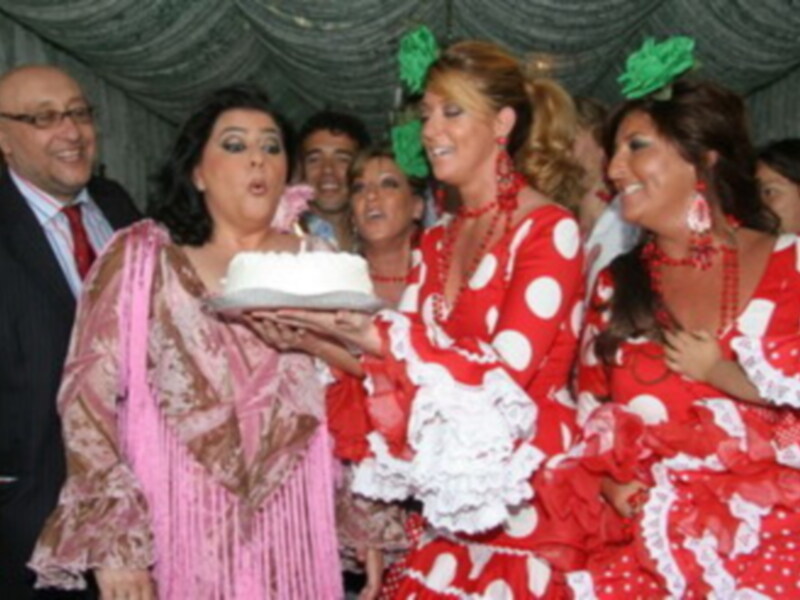 Fiesta tradicional con mujeres en trajes de flamenca celebrando con una torta.