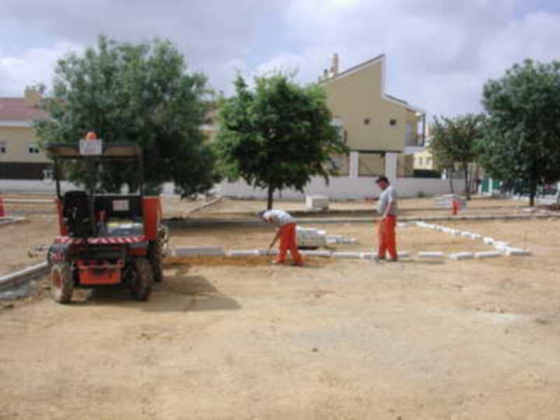 Trabajadores en una obra de construcción, colocando tuberías en un terreno baldío.