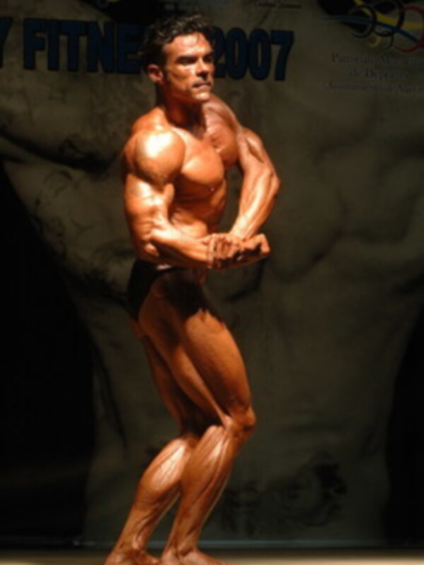 Un modelo de figura muscular en un fondo oscuro, posando con el torso hacia adelante y los brazos en la posición de flexión.