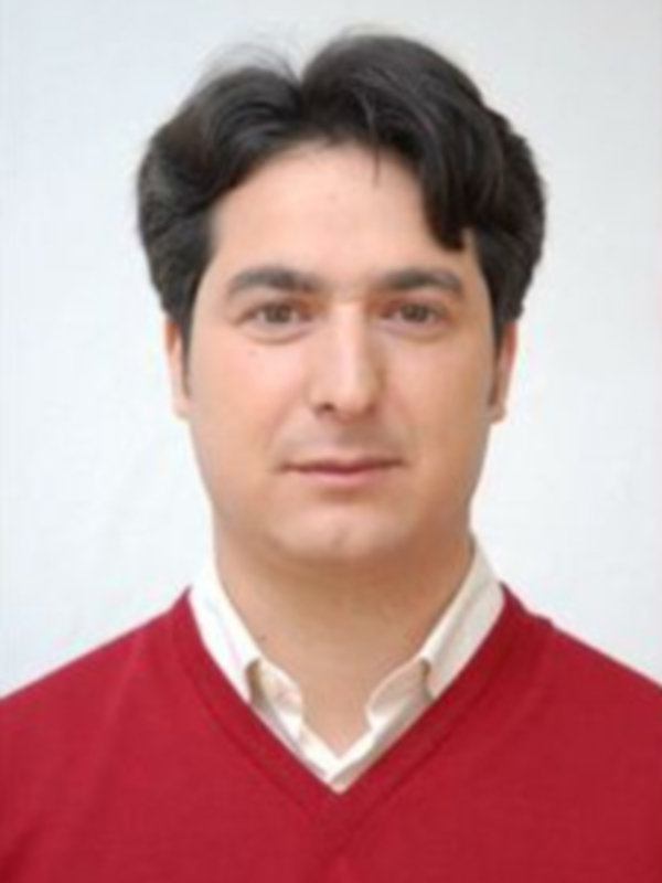 Retrato de hombre con suéter rojo y camisa blanca, fondo blanco.