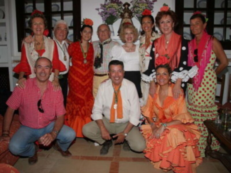 Grupo de personas vestidas con trajes típicos de flamenco posando juntos en un ambiente acogedor.