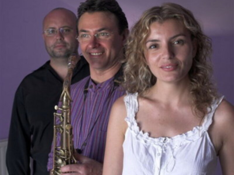 Tres músicos con saxofón en un estudio de fotografía con fondo púrpura.