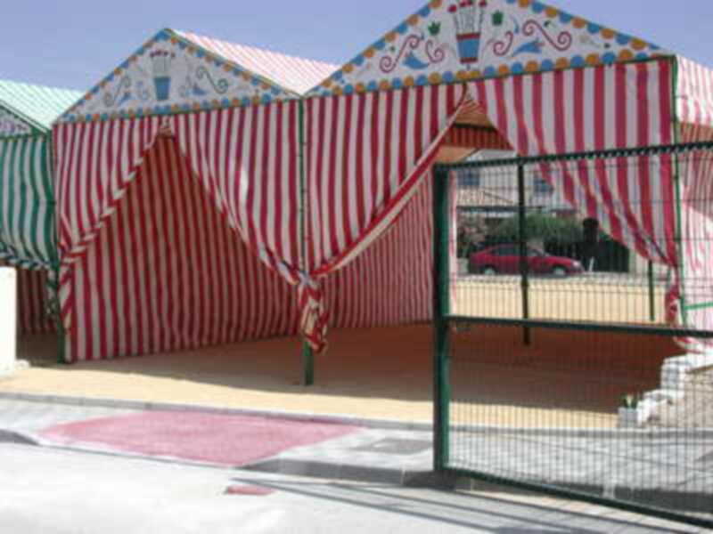 Carpa de circo con banderines y rayas rojas y blancas en un entorno urbano.