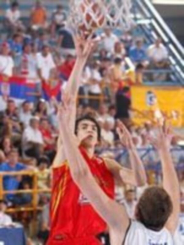 Jugador en acción durante un partido de baloncesto, realizando un mate en el aro.