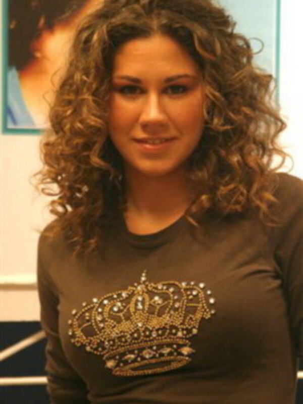 Una mujer con cabello rizado y una camiseta marrón con un diseño de corona en la parte superior.