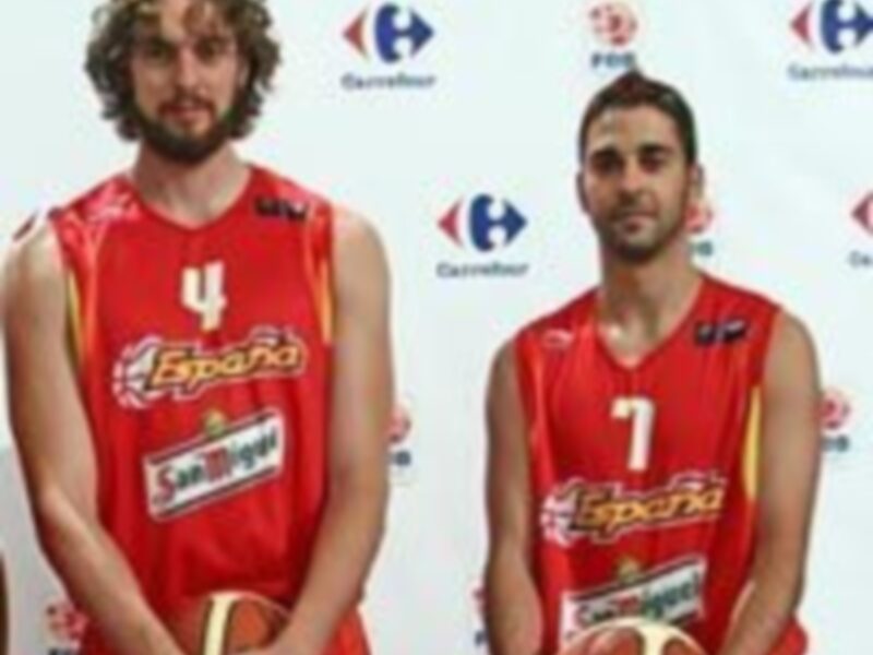 Jugadores de baloncesto con camisetas de España posando con balones de baloncesto.