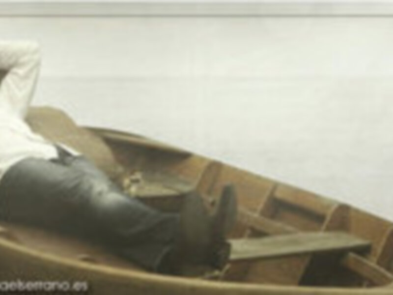 Hombre relajado en un sillón de madera, con un CD y álbum digital en el fondo.