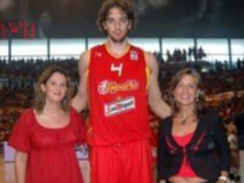 Jugador de baloncesto posando con dos mujeres en un evento deportivo.
